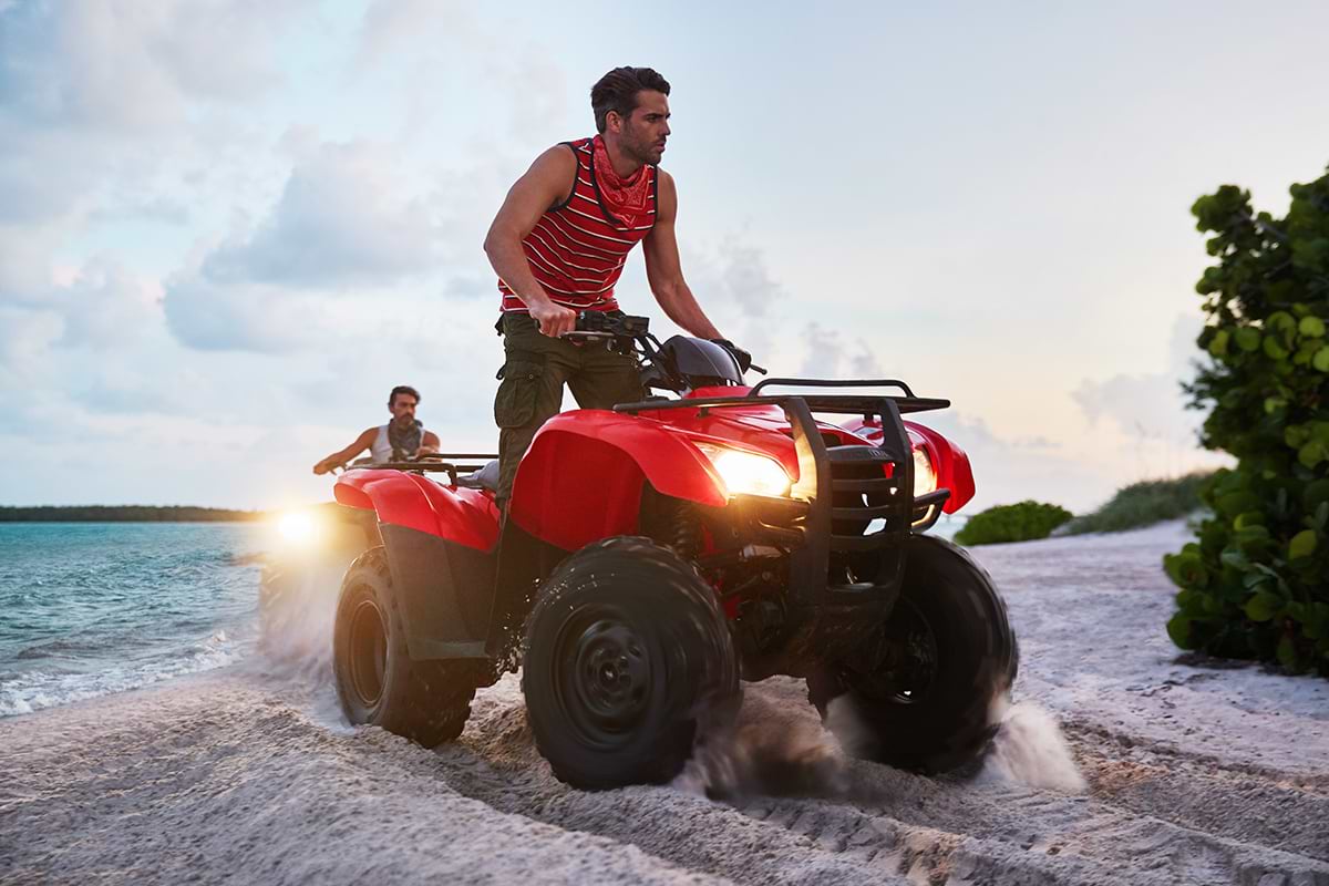 Two men driving ATVs at the beach